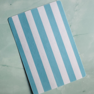 Insert décoratif Kindle "Summer Stripes" aux rayures bleu turquoise et blanc, posé sur fond marbre vert
