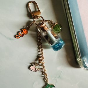 Bijou charm liseuse Mermaid Collection : chaîne dorée avec bouteille à message bleue, coquillage vert, poisson clown, baleine rose et queue de sirène verte