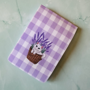 Marque-page magnétique "Lavande & Merveilles" : chaton blanc kawaii dans un panier en osier entouré de lavande violette sur fond vichy lilas et blanc, posé sur fond marbre vert