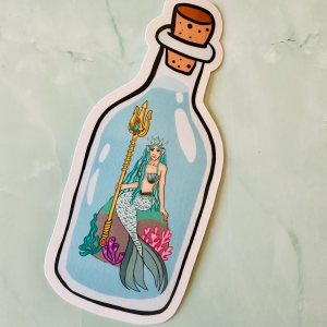 Marque-page die-cut "Siren in a Bottle" 13x5,5 cm : sirène royale couronnée au trident doré dans une bouteille à message bouchon liège, entourée de coraux et algues, posé sur fond marbre vert