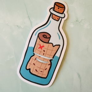 Marque-page die-cut "Treasure in a Bottle" 13x5,5 cm : carte au trésor froissée marquée d'un X rouge dans une bouteille à message bouchon liège et eau turquoise, posé sur fond marbre vert