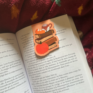 Marque-page magnétique die-cut "Autumn Book Club" : pile de livres brun chocolat avec tasse renard marshmallows et citrouille orange, posé sur un livre ouvert