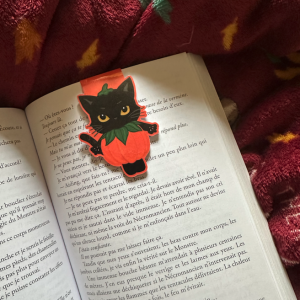 Marque-page magnétique die-cut "Potichat d'Automne" : chat noir kawaii aux yeux dorés déguisé en citrouille orange, posé sur un livre ouvert